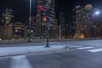 an empty city freeway at night with high rise buildings in the background with white and yellow lights