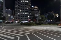 a crosswalk on the sidewalk between two buildings at night with bright lights illuminating from its windows