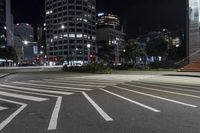 a crosswalk on the sidewalk between two buildings at night with bright lights illuminating from its windows