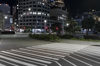 a crosswalk on the sidewalk between two buildings at night with bright lights illuminating from its windows