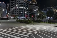 a crosswalk on the sidewalk between two buildings at night with bright lights illuminating from its windows