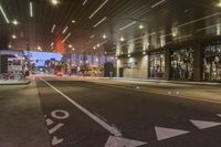 a street view at night with multiple light spots, multiple lights and signs on the sidewalk