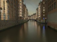 there are buildings along the water's edge at night, with lights reflecting off of the windows