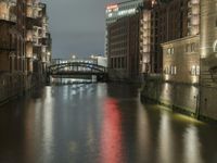 there are buildings along the water's edge at night, with lights reflecting off of the windows