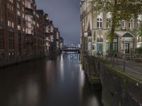 there are buildings along the water's edge at night, with lights reflecting off of the windows