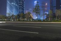 an empty street in a city with high buildings in the background at night time time