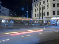 the view of an intersection in the city at night, including cars moving down the road