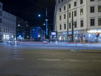 the view of an intersection in the city at night, including cars moving down the road