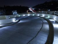 a large white ramp on the street at night with lit walkway lights on it and stairs