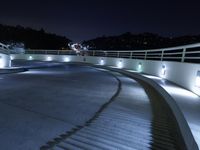 a large white ramp on the street at night with lit walkway lights on it and stairs