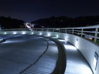 a large white ramp on the street at night with lit walkway lights on it and stairs