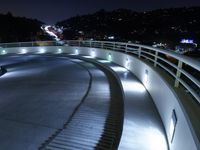 a large white ramp on the street at night with lit walkway lights on it and stairs