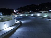 a large white ramp on the street at night with lit walkway lights on it and stairs