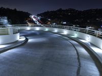 a large white ramp on the street at night with lit walkway lights on it and stairs