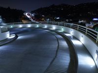 a large white ramp on the street at night with lit walkway lights on it and stairs