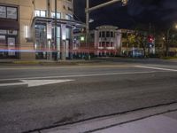 the traffic signal on the corner of the road is lit up at night time with a large building on the opposite side