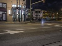 the traffic signal on the corner of the road is lit up at night time with a large building on the opposite side