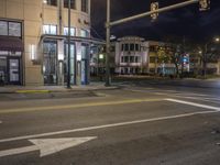 the traffic signal on the corner of the road is lit up at night time with a large building on the opposite side