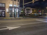 the traffic signal on the corner of the road is lit up at night time with a large building on the opposite side