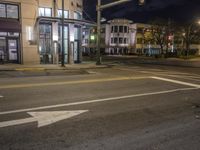 the traffic signal on the corner of the road is lit up at night time with a large building on the opposite side