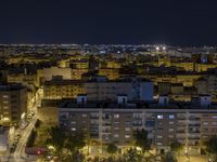 the town lights shine bright in this nighttime scene of madrid, with buses and cars on it
