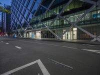 a city street at dusk near tall buildings with lights in the windows, the blue street lights are shining