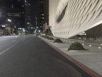 a white building sitting next to a road at night time in the city street corner