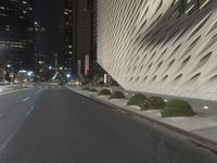 a white building sitting next to a road at night time in the city street corner