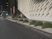 a white building sitting next to a road at night time in the city street corner