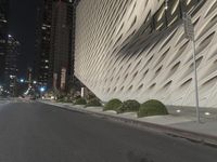 a white building sitting next to a road at night time in the city street corner