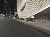 a white building sitting next to a road at night time in the city street corner