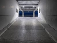 a walkway under construction with metal grates and door open onto the ocean shore at dusk