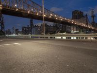 an empty road on a city street near the water at night, with streetlights glowing down