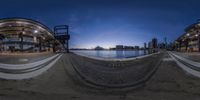 the 360 view shows people on the shore at night in the distance are a clock and water