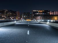 an empty street with white curved pedestrian crossing bridges at night time in the middle of a city