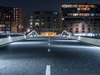 an empty street with white curved pedestrian crossing bridges at night time in the middle of a city