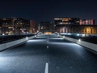 an empty street with white curved pedestrian crossing bridges at night time in the middle of a city