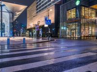 a view of a pedestrian crossing across from some other street lights at night time, with buildings in the background