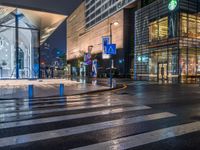 a view of a pedestrian crossing across from some other street lights at night time, with buildings in the background