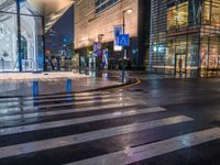 a view of a pedestrian crossing across from some other street lights at night time, with buildings in the background