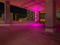 a pink light shines through the concrete in a building area with skyscrapers behind it