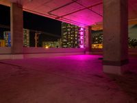 a pink light shines through the concrete in a building area with skyscrapers behind it