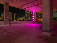 a pink light shines through the concrete in a building area with skyscrapers behind it