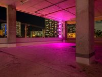 a pink light shines through the concrete in a building area with skyscrapers behind it