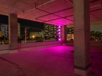 a pink light shines through the concrete in a building area with skyscrapers behind it