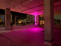 a pink light shines through the concrete in a building area with skyscrapers behind it