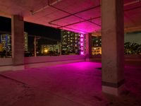 a pink light shines through the concrete in a building area with skyscrapers behind it