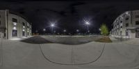 a person on a skate board in a parking lot at night time with building lit up