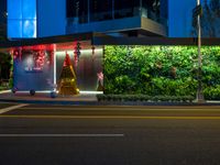 a street at night with a christmas tree and decorations on the wall next to it