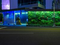 a street at night with a christmas tree and decorations on the wall next to it